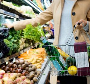 Mulher comprando produtos alimentícios, ela tem uma garrafa de vidro com o código de barras virado para câmera 